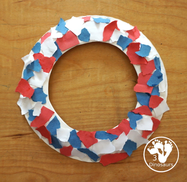Red, White, & Blue Torn Paper Wreath is a fun wreath you can make with kids. You use torn paper of red, white, and blue glued on the wreath. A simple idea for the Fourth of July for kids. 3Dinosaurs.com